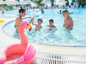 Children having fun and playing in an outdoor swimming pool on a bright summer day.